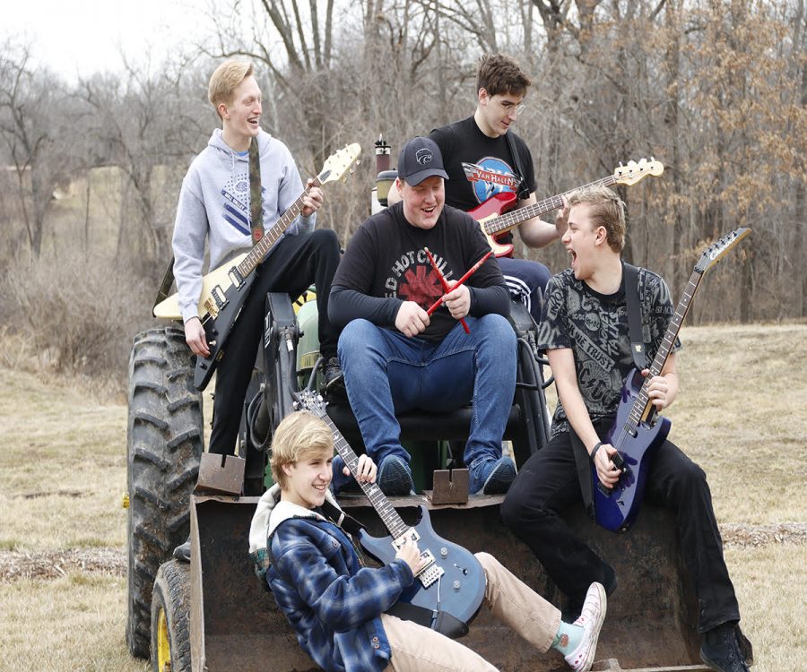 Holding their instruments, sophomore Anthony Molinaro and his band “Holiday Drive” pose for a picture while sitting on a tractor during band practice Thursday, Feb. 25. The band practices most Sundays. “The practices consist of us playing covers, our own songs and messing around,” Molinaro said.