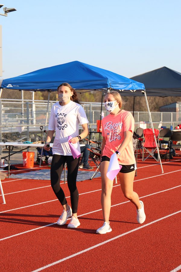 Holding their purple paper, sophomores Madison McClure and Avery Blubaugh walk the survivor lap to kick off the event.
