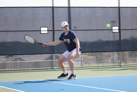 While swinging his racket back, junior Ben Fitterer follows the ball with his eyes.