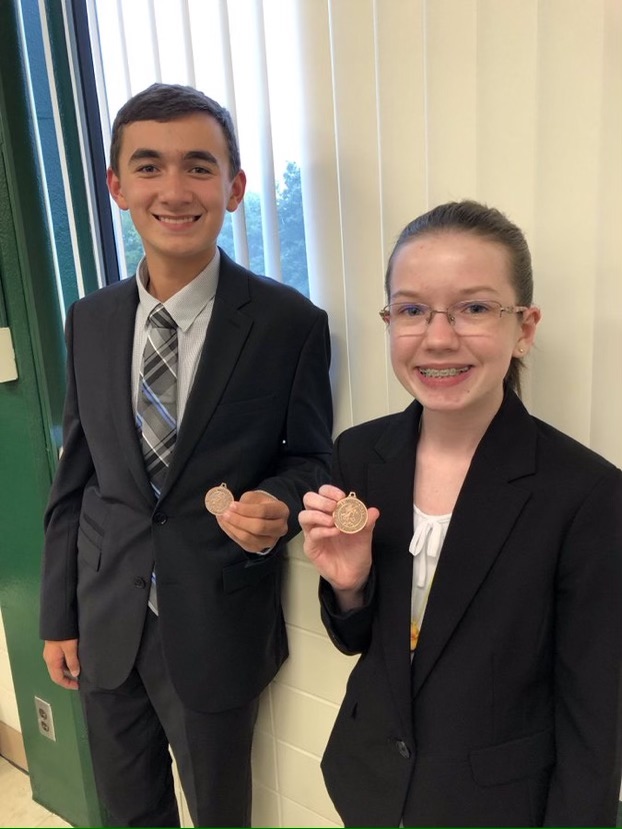 Posing with their medals, sophomores Sarah Johnston and Isaac Steiner smile with their award from a previous debate tournament Oct. 5 2019.