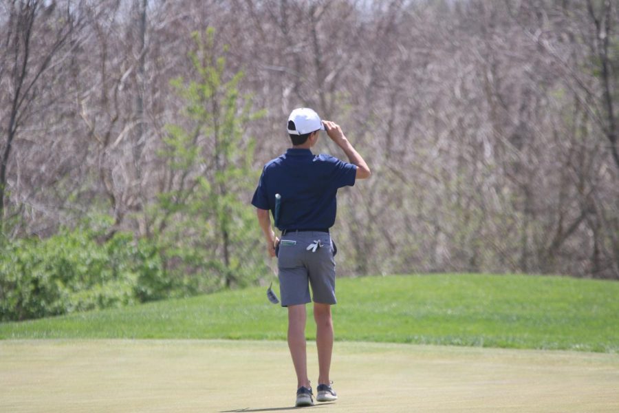 Waiting his turn to hit, sophomore Codey Geis readjusts his hat.