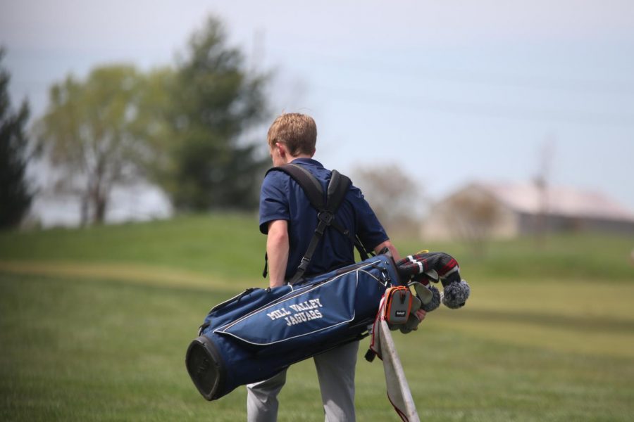 Making his way to the next hole, sophomore Matt Morgan carries his clubs.