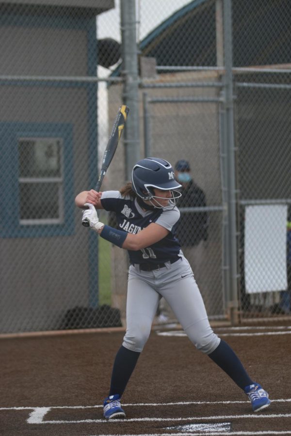 With the bat above her head, sophomore Adisyn Hopkins prepares to swing for the ball.