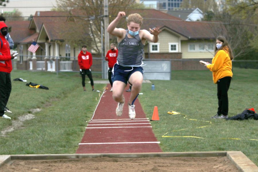 In the air, sophomore Noah Coy throw himself forward as far as he can into the long jump pit.