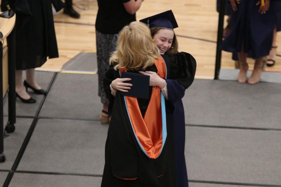 As she walks across the stage, senior Cali Rhodes stops to hug principal Gail Holder.