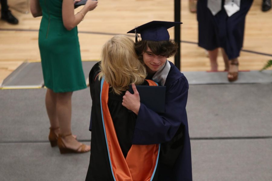 With his diploma in his hand, senior Noah McCoy hugs principal Gail Holder.