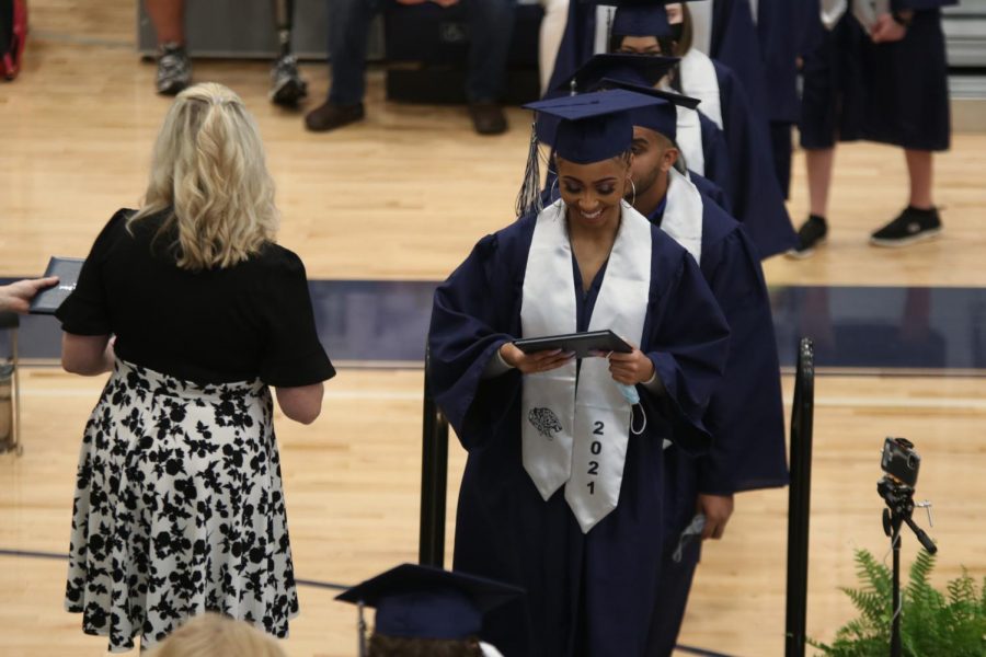 Smiling with her diploma, senior Vania Barnett walks across the stage.