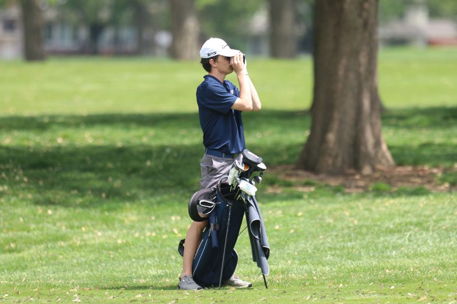 Checking the distance, junior Jack Dedrickson looks to see  how far away the hole is from where he’s putting. 