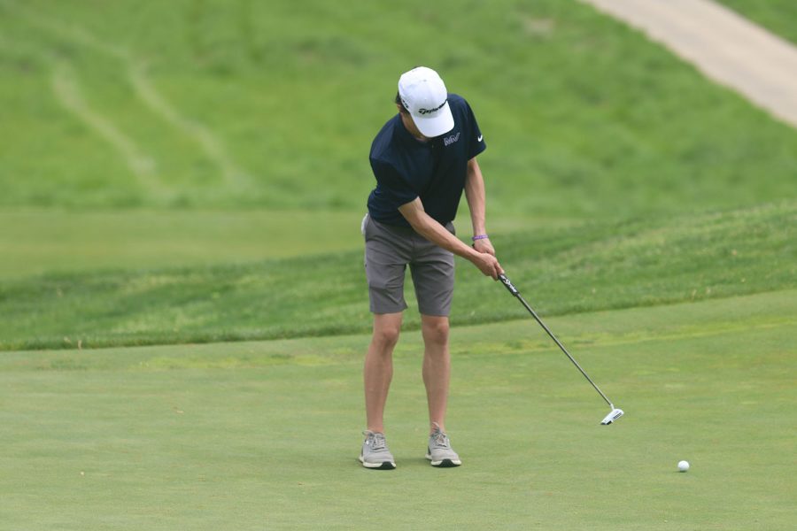Paying close attention to the ball, junior Jack Dedrickson putts the golf ball.