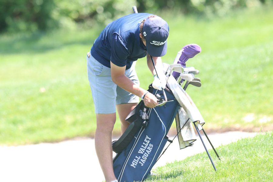 Getting ready, senior Nick Mason cleans his golf club with a brush.