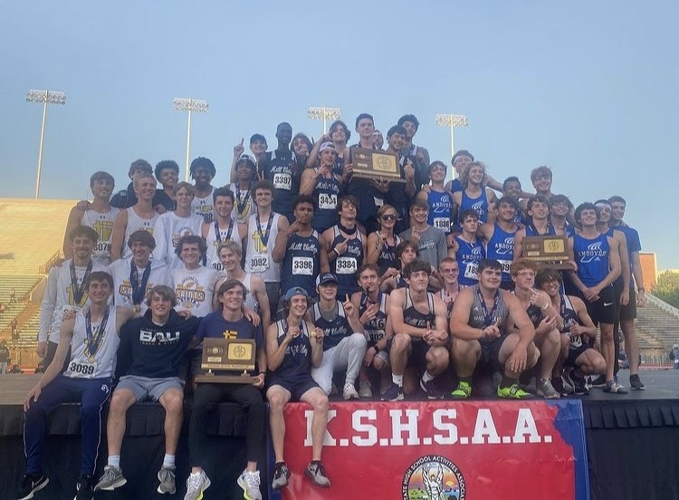 Throwing up the number one, the boys track team stand on the podium with their state championship trophy to commemorate winning the first state title in track and field in Mill Valley history.