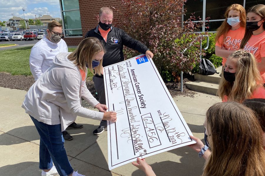 Counselor Erin Hayes signs the ceremonial check presented to McKenzie Marshall from the American Cancer Society Wednesday, May 12.