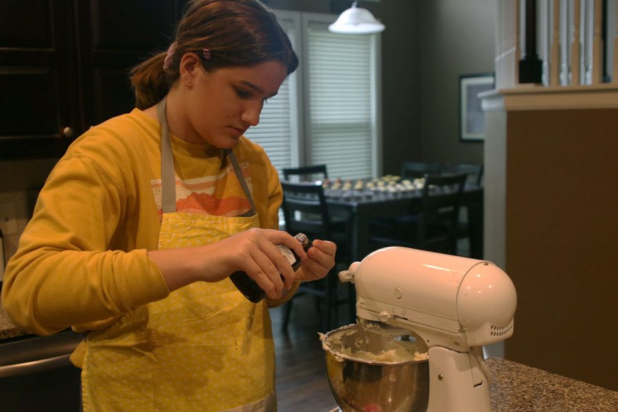 While combining the ingredients for her homemade buttercream, freshman Lauren Prestia measures vanilla extract to add to the mixture.