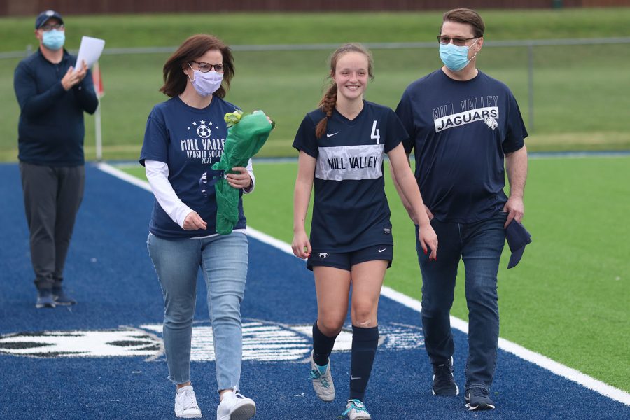 Walking with her parents, senior girls soccer player Hannah Beashore smiles as she approaches the middle of the field. 