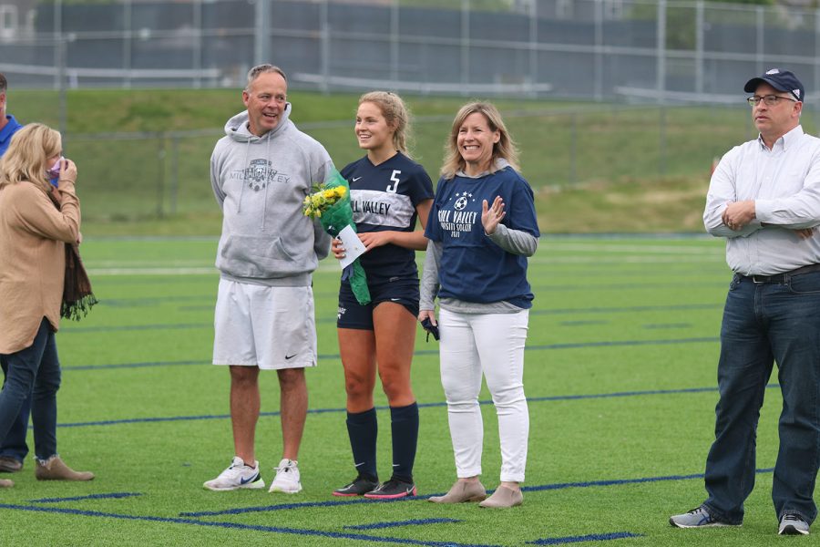 Standing with her parents, senior girls soccer player Molly Ricker holds a bouquet of flowers.