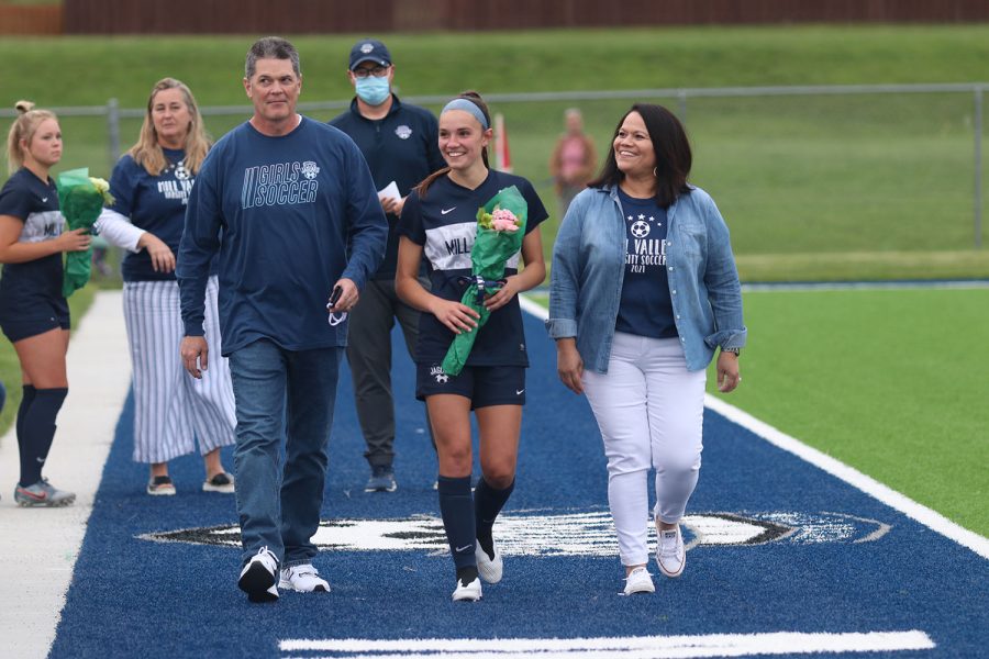 Walking with her parents, senior girls soccer player Peyton Wagoner holds a bouquet of flowers.