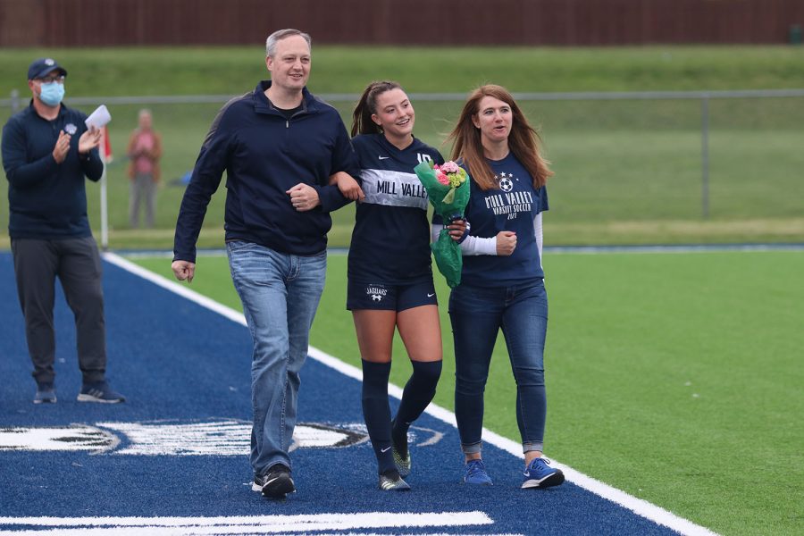 Walking with her parents, senior girls soccer player Katherine Weigel holds a bouquet of flowers as she approaches the middle of the field during girls soccer senior night on Friday, May 7.