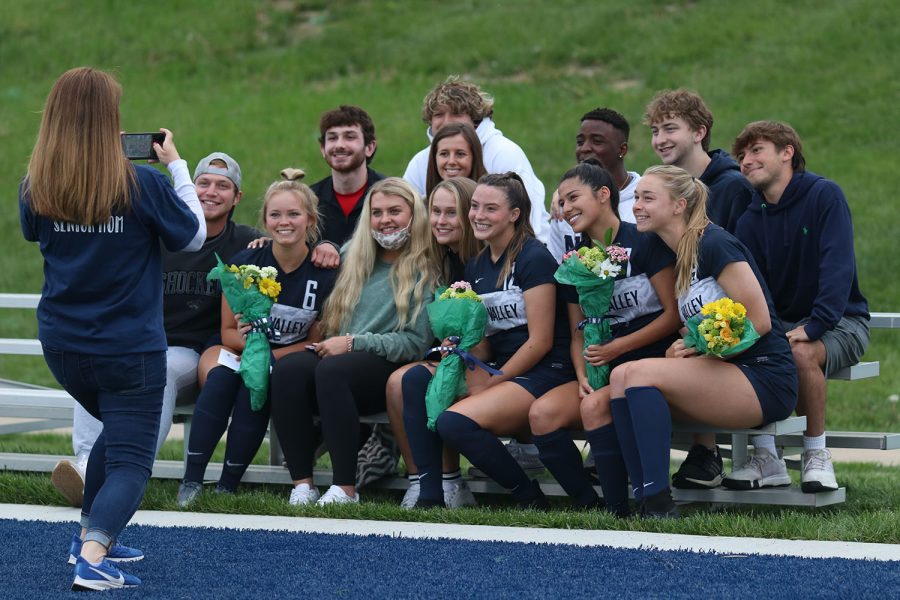 Posing for a photo, senior members of the girls soccer team hold their bouquet of flowers while smiling with their peers during senior night.