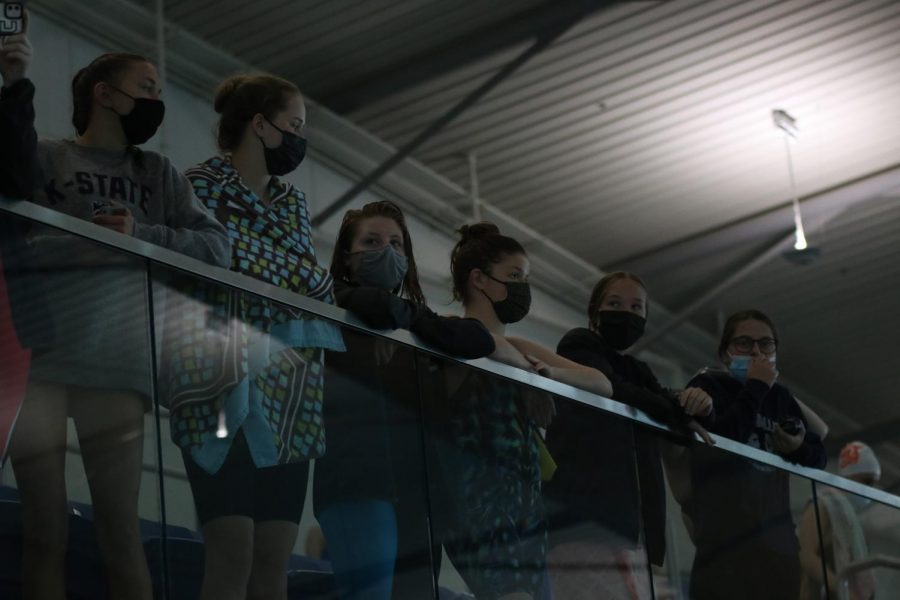 Leaning on the rail, the team cheers on their swimmers.