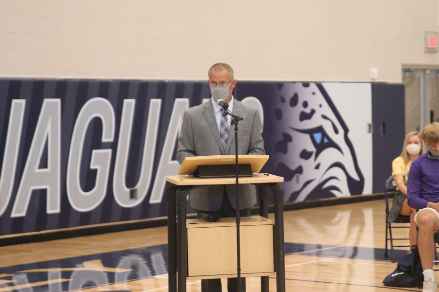 Standing at the podium in the main gym, athletic director Jerald VanRheen announces how the ceremony will proceed. 