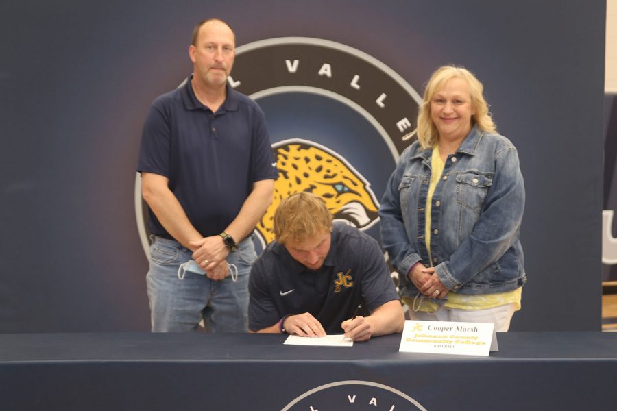 Senior Cooper Marsh signs and poses with his parents. Marsh will attend Johnson County Community College for baseball.