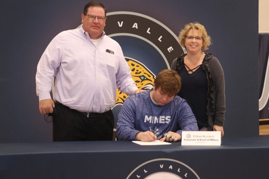 Senior Ethan Kremer signs and poses with his parents. Kremer will attend Colorado School of Mines for wrestling.