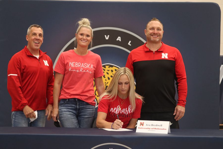 Senior Ava Bredwell signs and poses with her parents. Bredwell will attend University of Nebraska for softball.