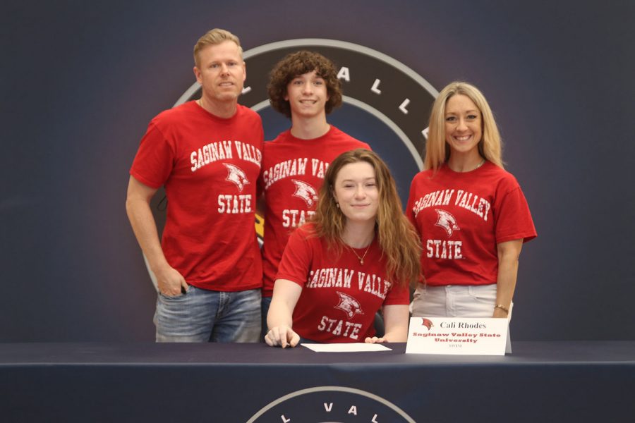 Senior Cali Rhodes signs and poses with her parents. Rhodes will attend Saginaw Valley State University for swim.