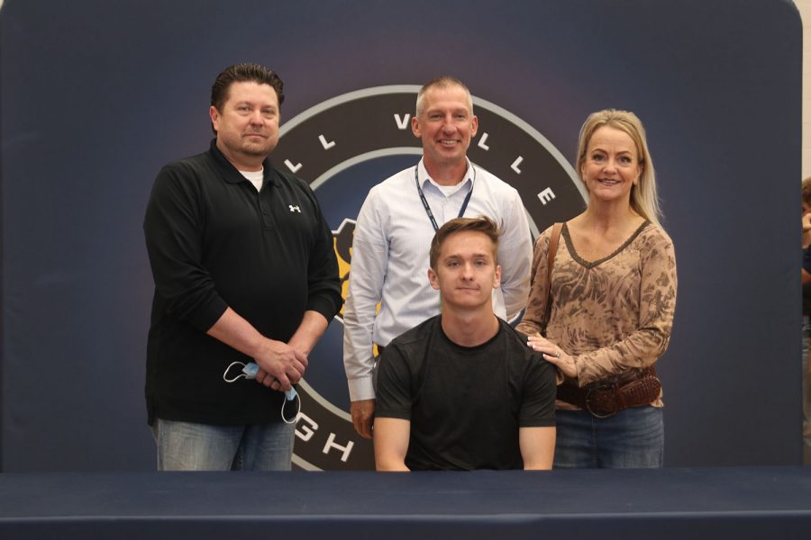 Senior Carysn Turpin signs and poses with his parents and coach McAfee. Turpin will attend Hutchinson Community College for track and field and cross country.
