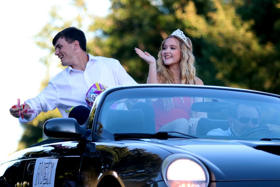 With a smile on his face, Homecoming king candidate senior Nick Brubeck throws candy from the car to the children on the side of the road while his partner Homecoming queen candidate senior Avery Davis waves to the crowd.