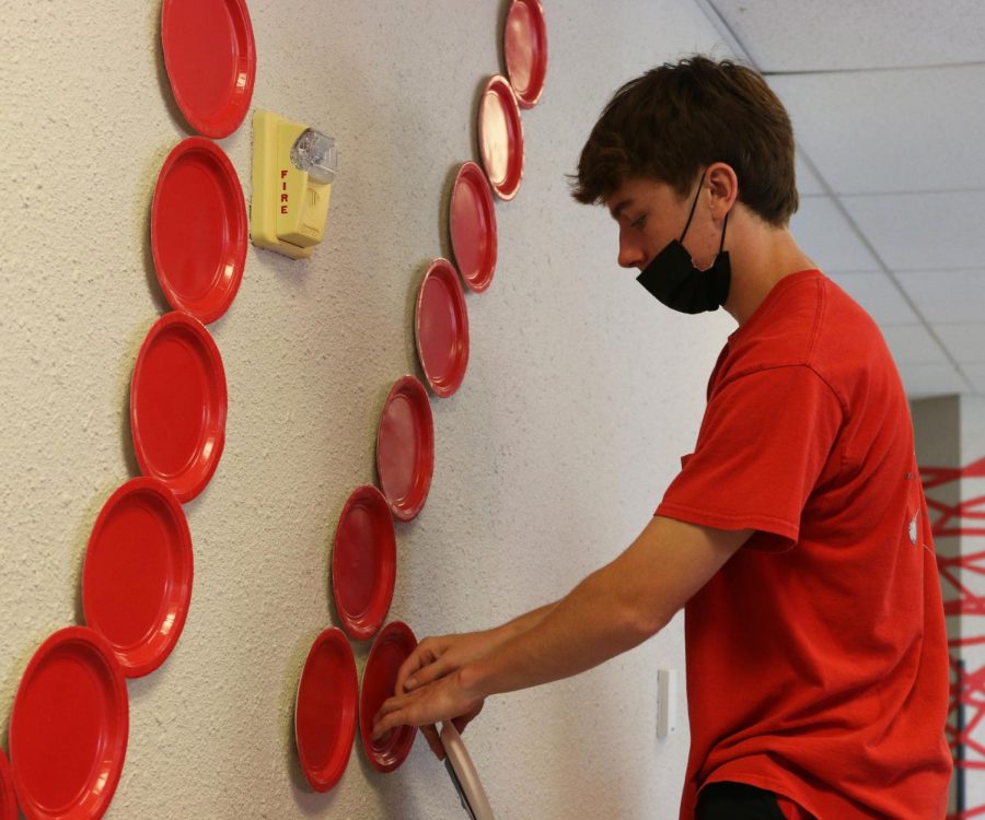 Taping plates to the wall, junior Toby Kornis spells out 2023
