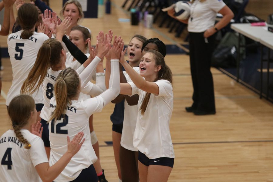 As the starting players run onto the court, the rest of the varsity team high fives and cheers.