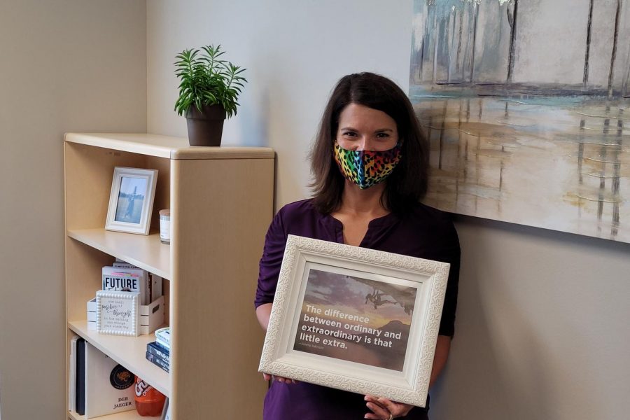 In her office, assistant Principal Deb Jaeger poses with a framed photo of her favorite quote in hand.