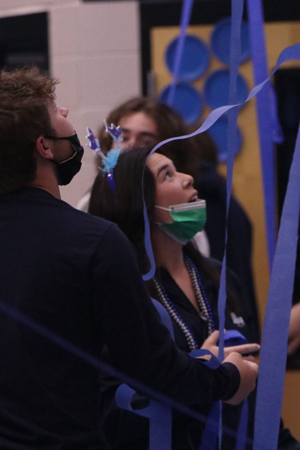 Standing in the main foyer, senior Eden Schanker watches as blue streamers float in the air.