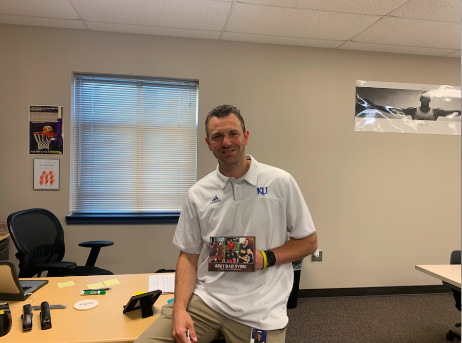Business teacher Adam Runyan holds a picture of his family in front of his desk. Runyan looks forward to creating a great environment for his students while also building the girls basketball program. 