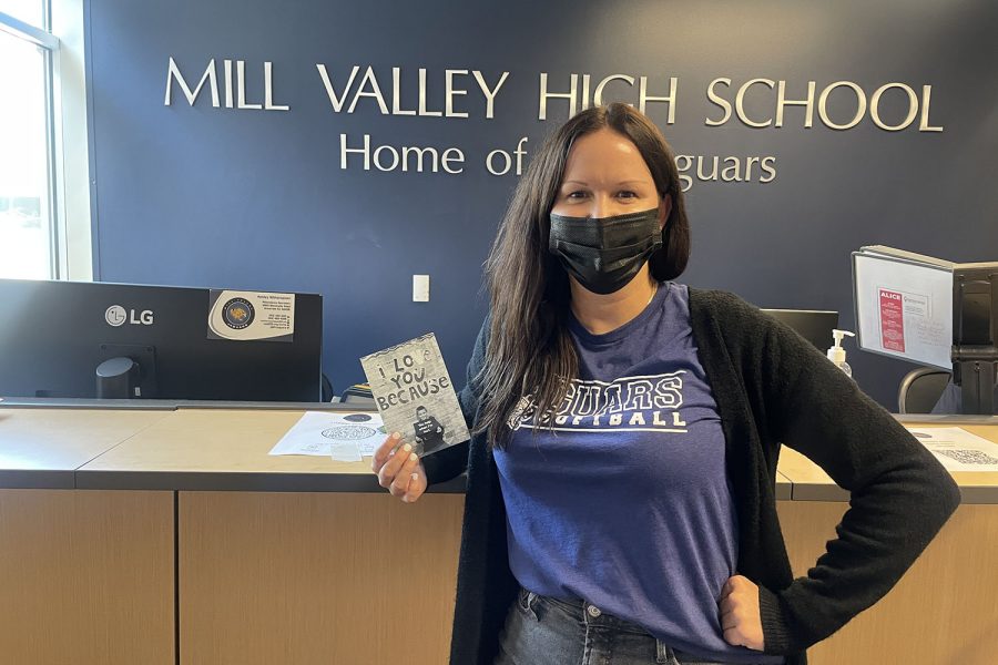 Holding a photo of her son, secretary Ashley Witherspoon poses at her desk in the front office. She is looking forward to football season and getting involved with other sports.