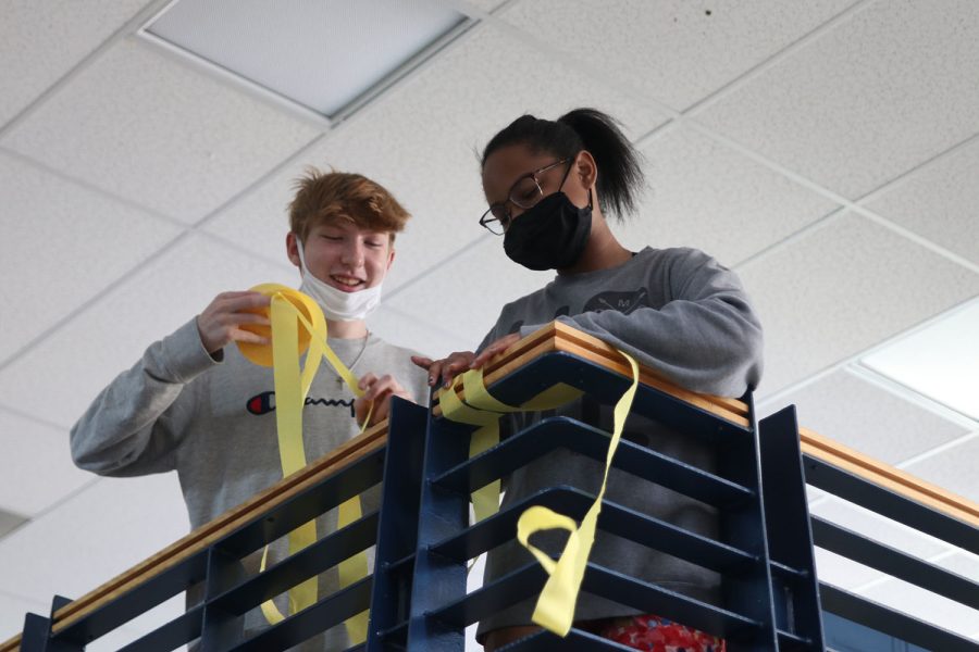 Working as a team, freshmen Logan Koester and Autumn Graves wrap streamers around the railing. 
