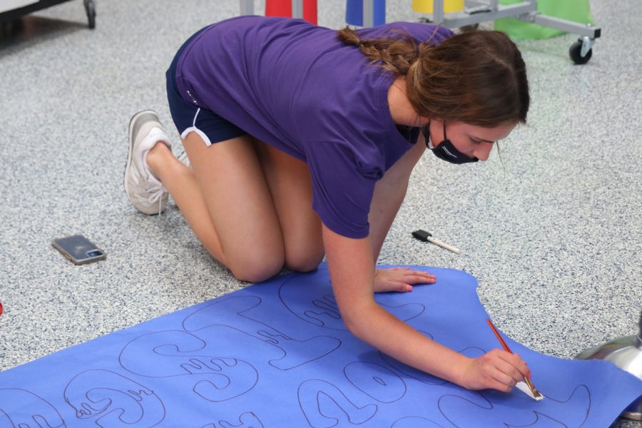 Paintbrush in hand, senior Logan Pfeister works on filling in the letters on a sign. 