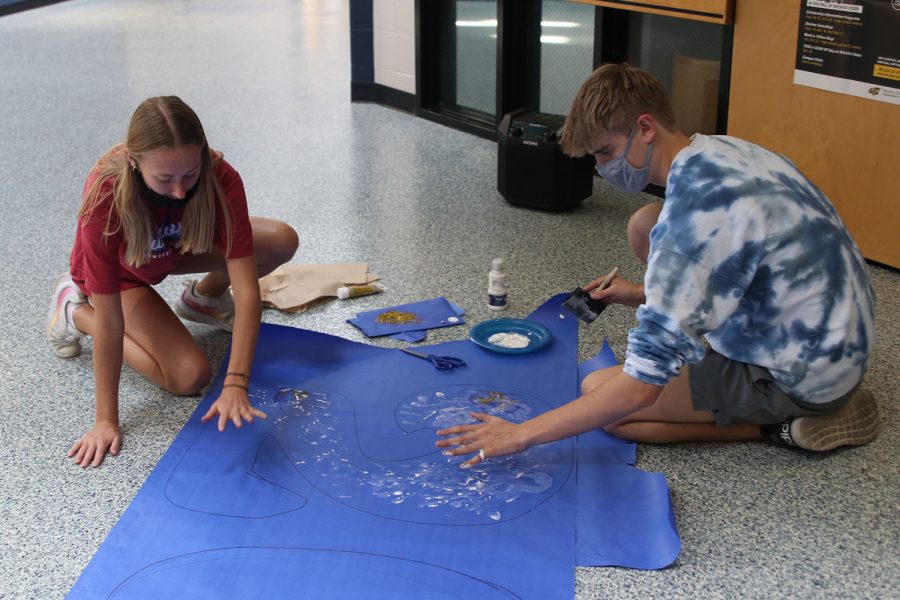 Hands out, seniors Carly Hey and Bret Weber use handprints to add detail to their poster. 
