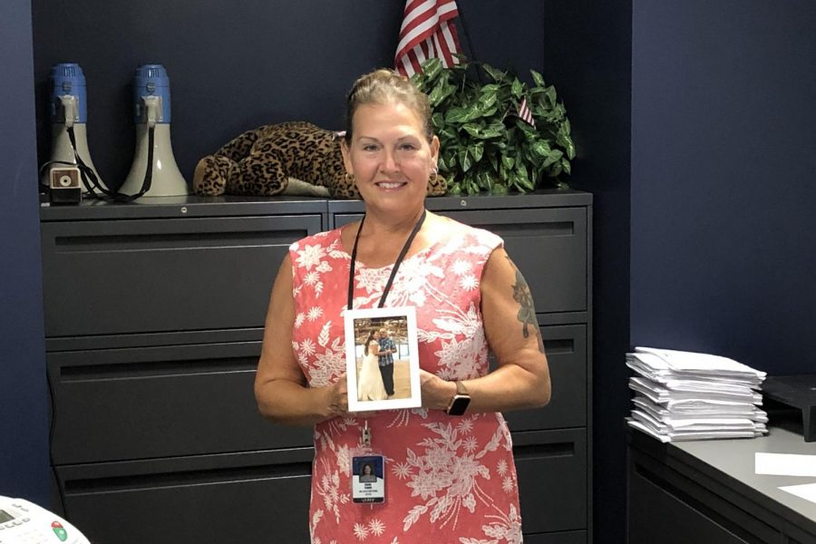 Athletic secretary Linda Logan poses with a photo that was taken of her and her father at her wedding. Logan is excited to help as many people as she can this year.