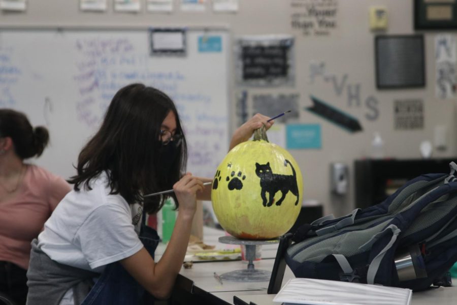 Carefully painting cat prints, Sophie Hsu puts the final touches on their pumpkin.