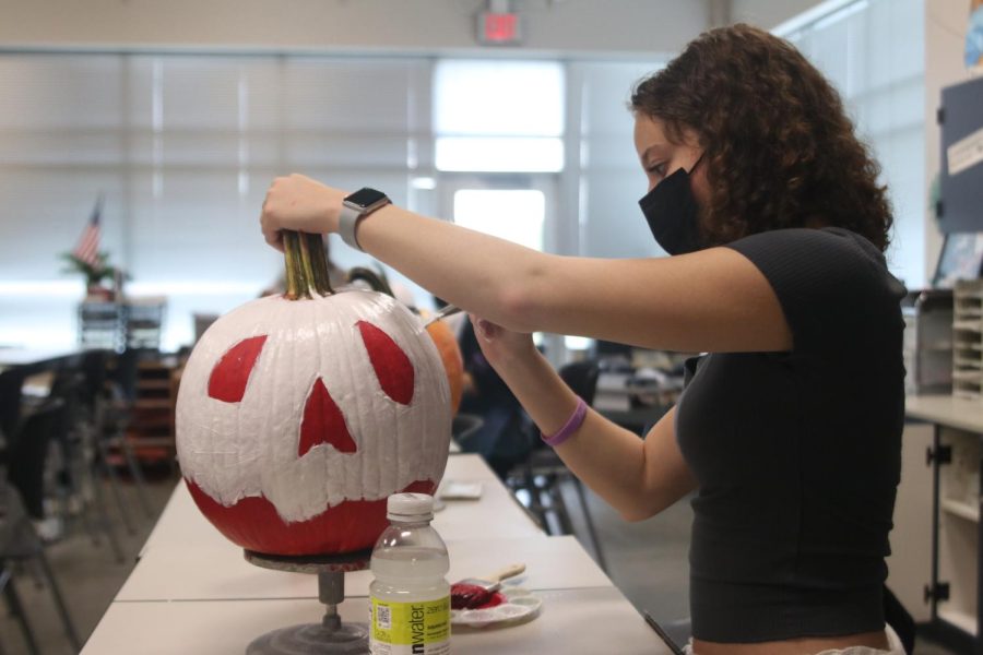 Touching up her pumpkin, junior Alex Cobin works on finishing up her final layer of white.