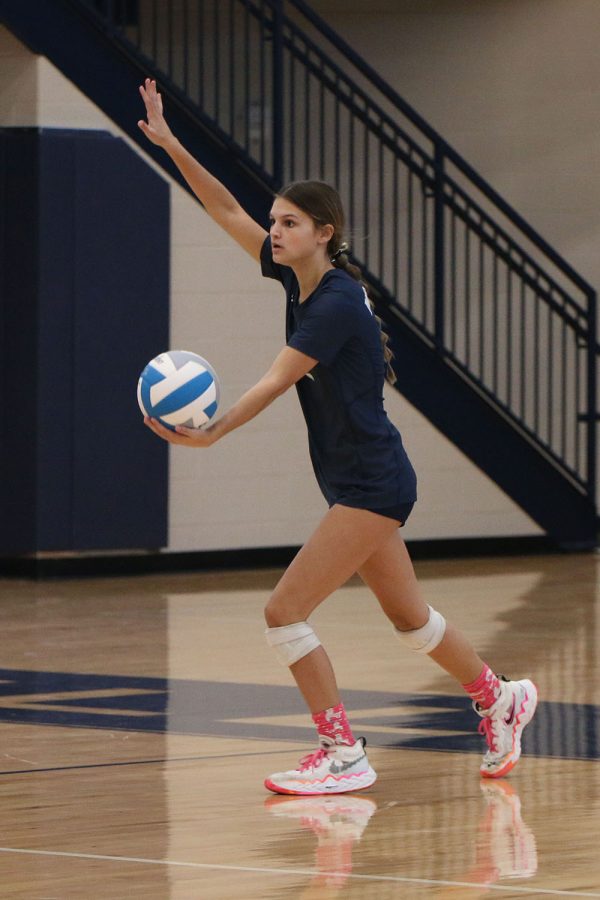 With her hand in the air, sophomore Ava Jones prepares to serve the ball over the net.