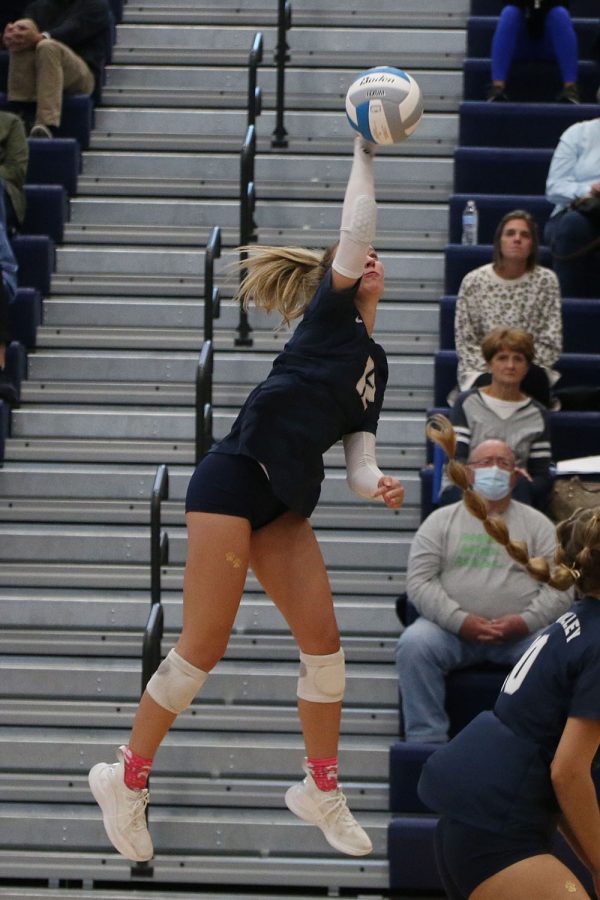 Eyes on the ball, junior Madeline Schnepf jumps in the air to hit the ball over the net.