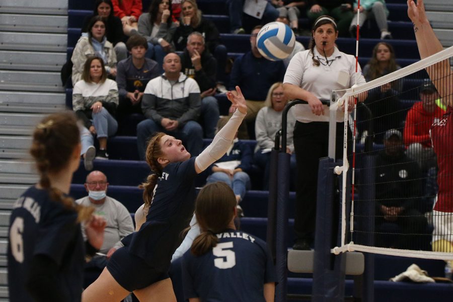 As the other team prepares to block, senior Brylee Peterson leans forward to hit the ball.