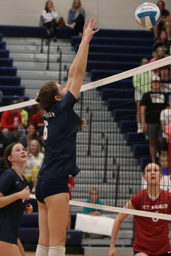 Reaching her hands up in the air, sophomore Kaitlyn Burke attempts to block the ball coming from a SJA player.