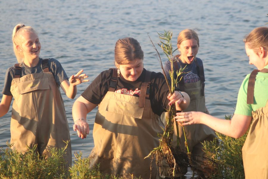 While the group members around her smile, senior Avery Warren shows off a good plant root she found.