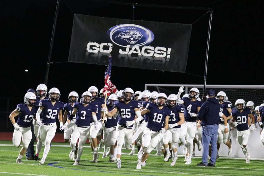Leading his fellow teammates onto the field, senior Jason Smith runs out of the tunnel holding the American flag high. 