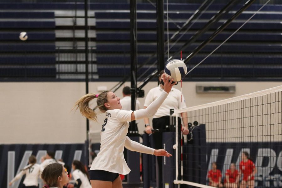 Jumping up, junior Madeline Schnepf stops the ball, sending it back toward Shawnee Mission North.