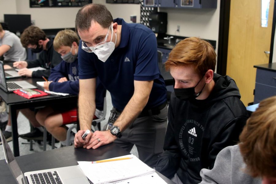 Science teacher Ryan Johnston helps out junior Owen Prosser with a question on a physics assignment.